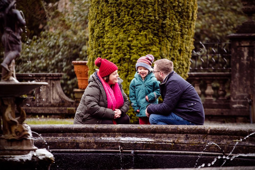 Family gathered on stone steps surrounded by moss-covered walls in a garden setting.