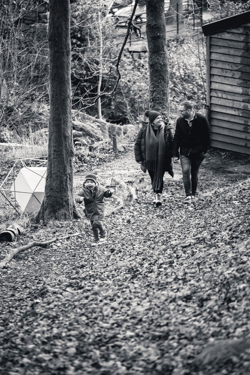 Black and white photo of people enjoying a woodland walk near a cabin.