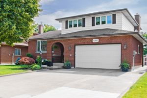 Two-story brick house with white garage door and blue shutters on landscaped suburban lot.