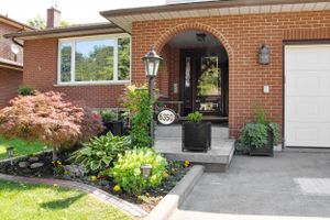 Exterior view of a brick house with landscaped garden and concrete driveway.
