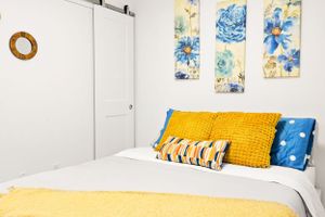 Bright bedroom with yellow accents, blue floral artwork, and sliding barn door.