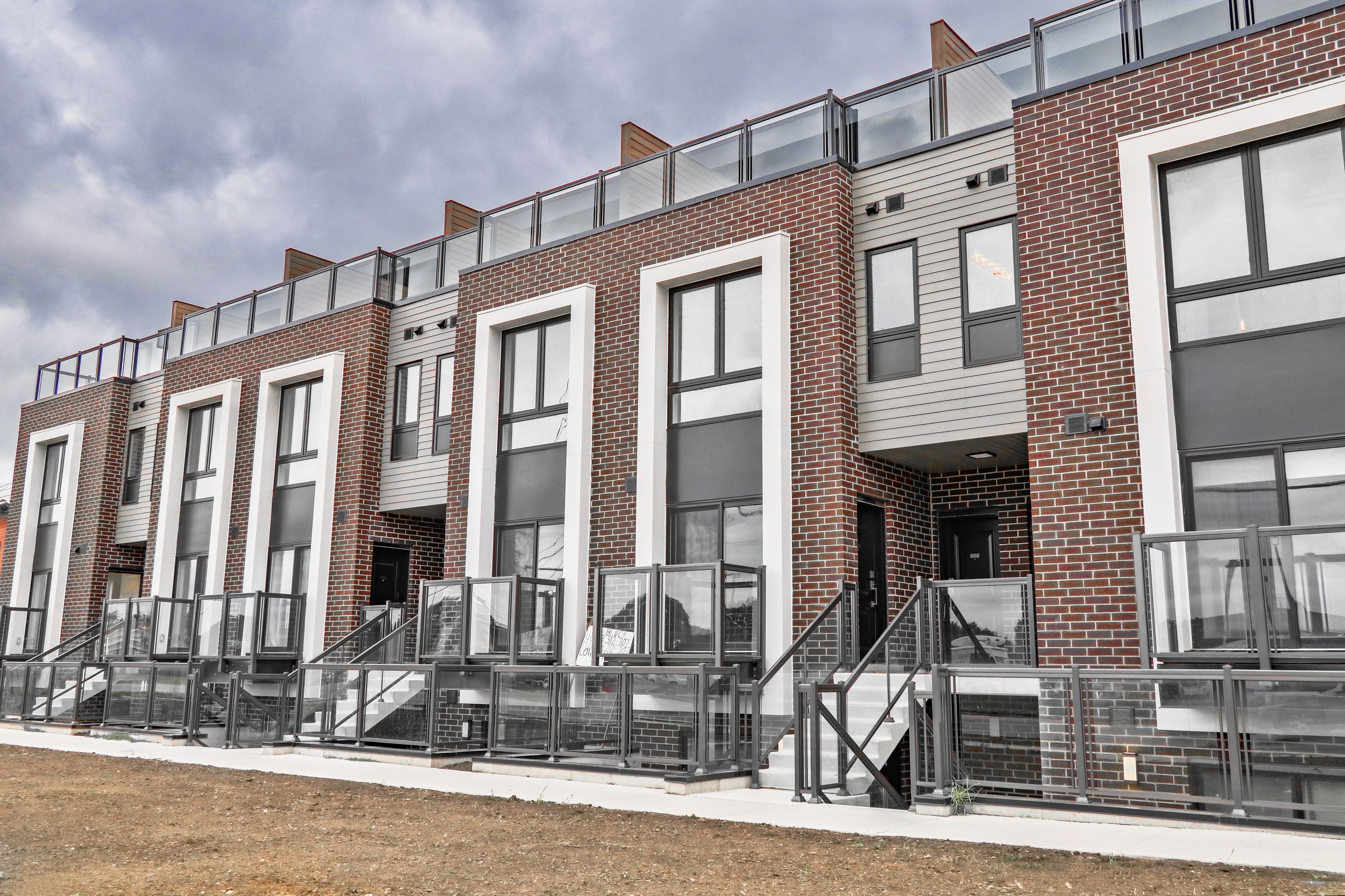 Modern townhouse complex with brick facade and glass balcony railings.