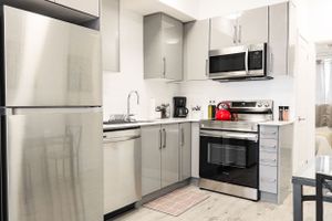 Modern kitchen with stainless steel appliances and light gray cabinets in a galley layout.