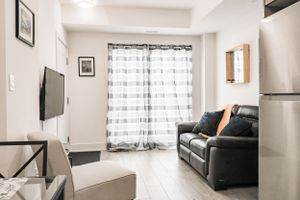 Contemporary living room with leather sofa, striped curtains, and wall-mounted TV.
