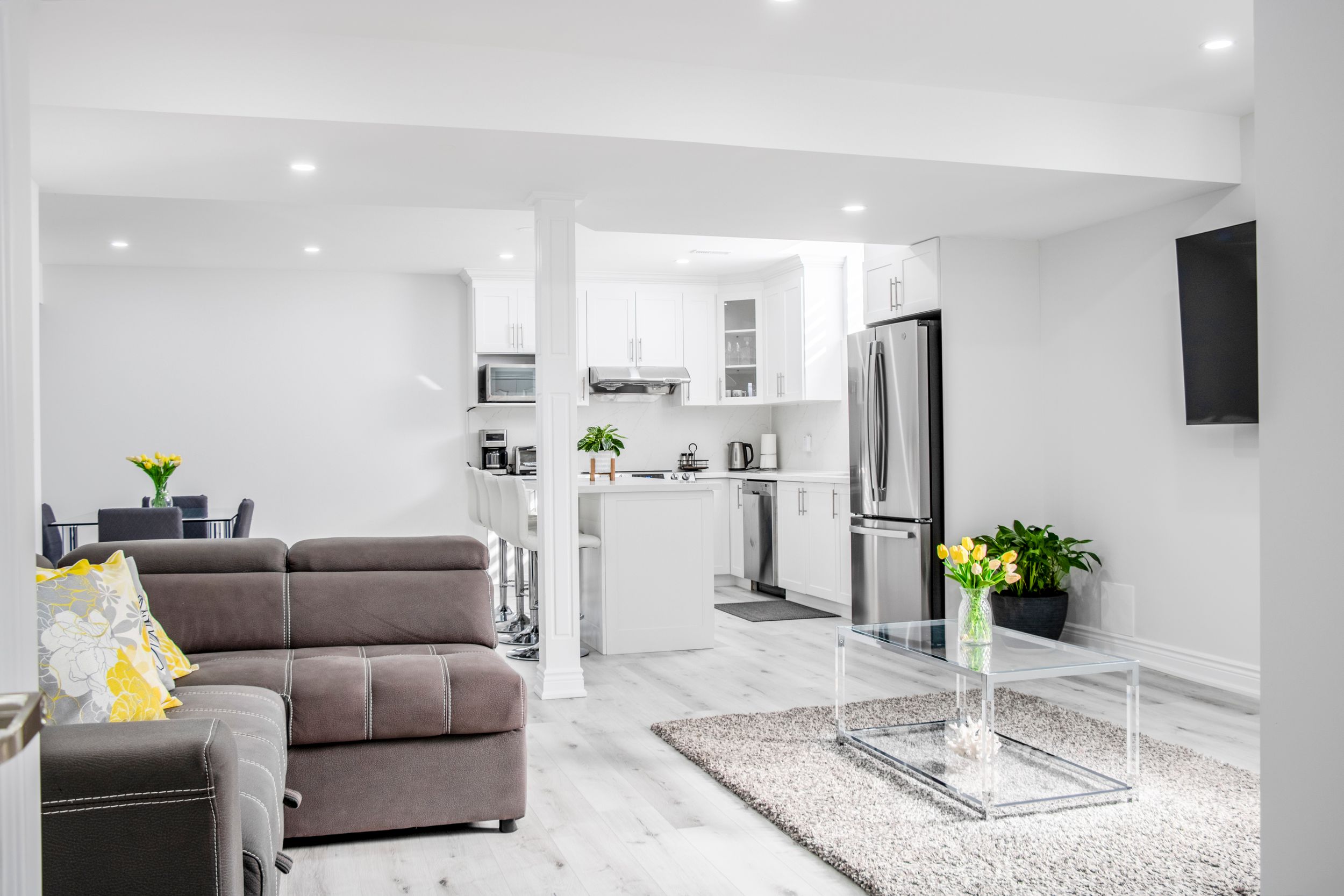 Spacious white basement living area with grey sofa and modern finishes.