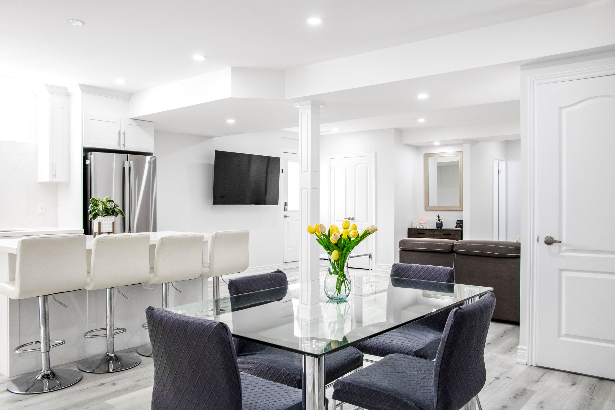 Modern white basement renovation with recessed lighting and contemporary furniture.