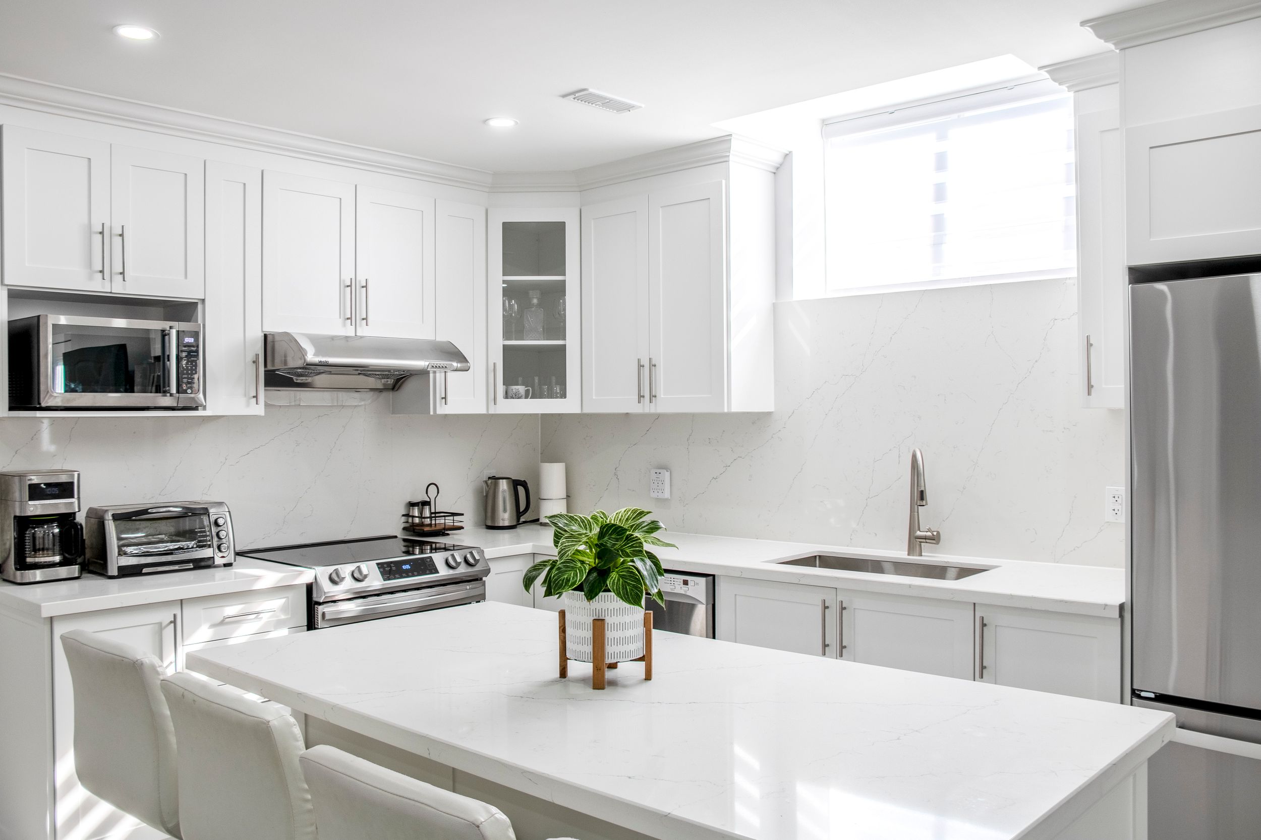 Bright white modern kitchen with stainless steel appliances and clean minimalist design.