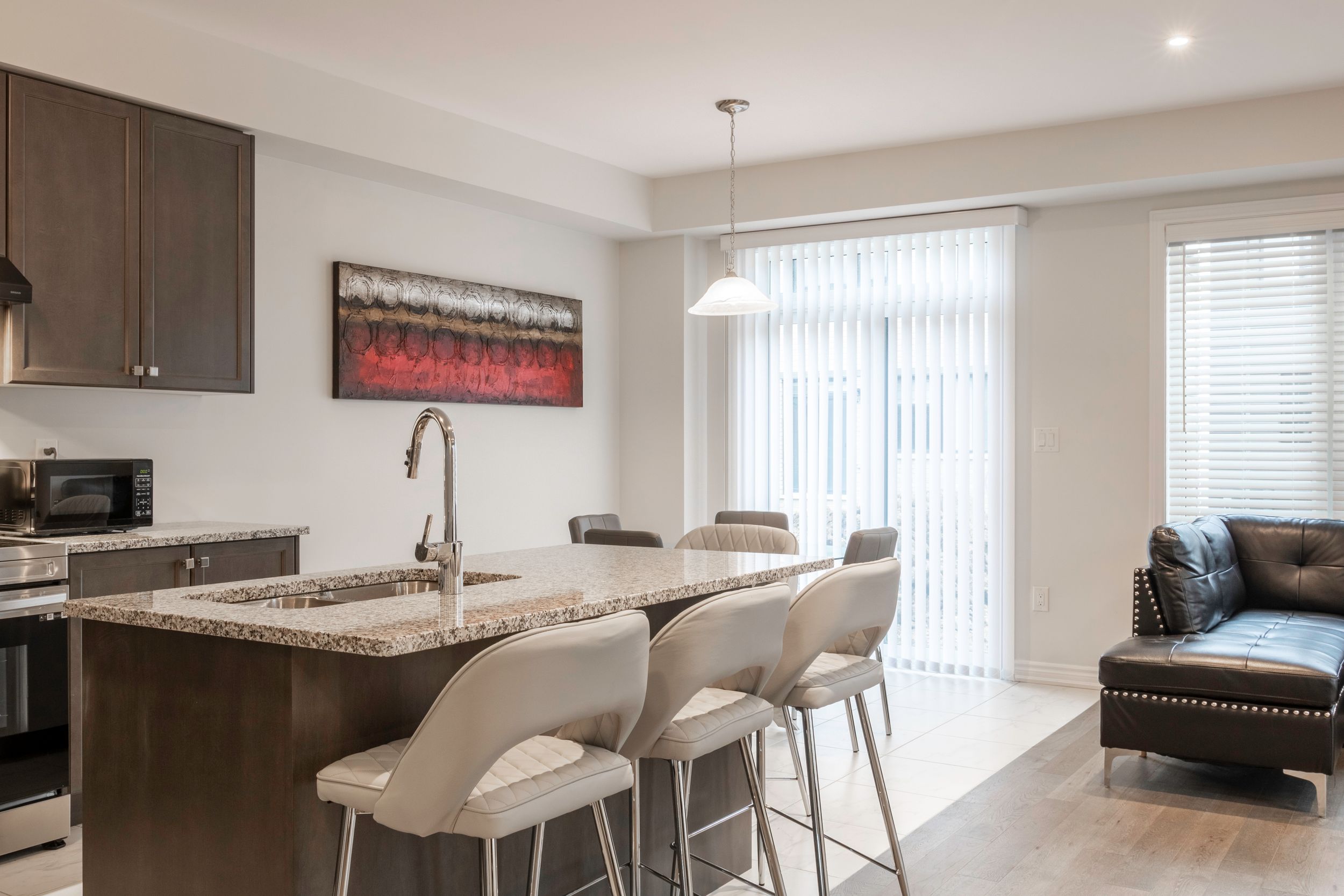 Contemporary kitchen and dining area with dark wood cabinets and white countertops.
