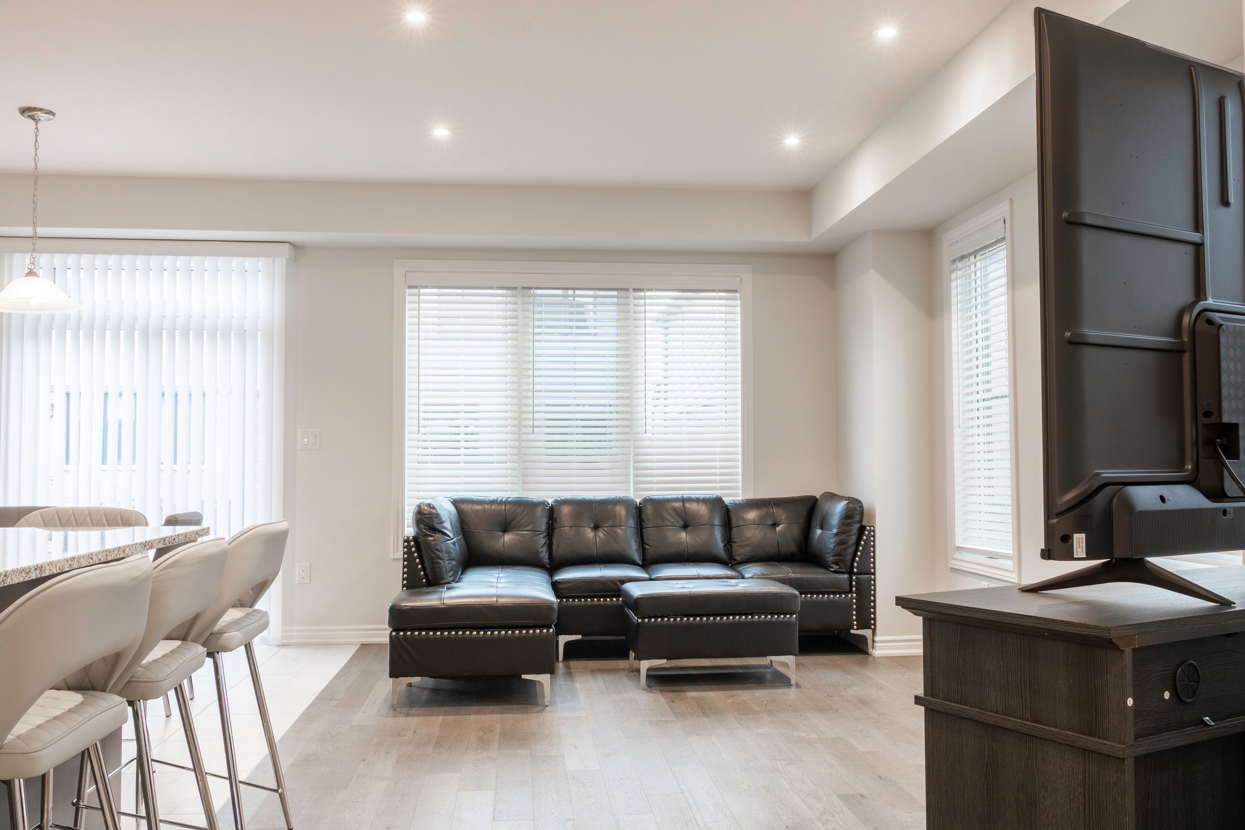 Modern open concept living room with recessed lighting and leather sectional sofa.