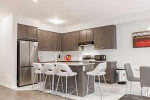 Spacious modern kitchen with brown cabinets and white countertops in an open floor plan.