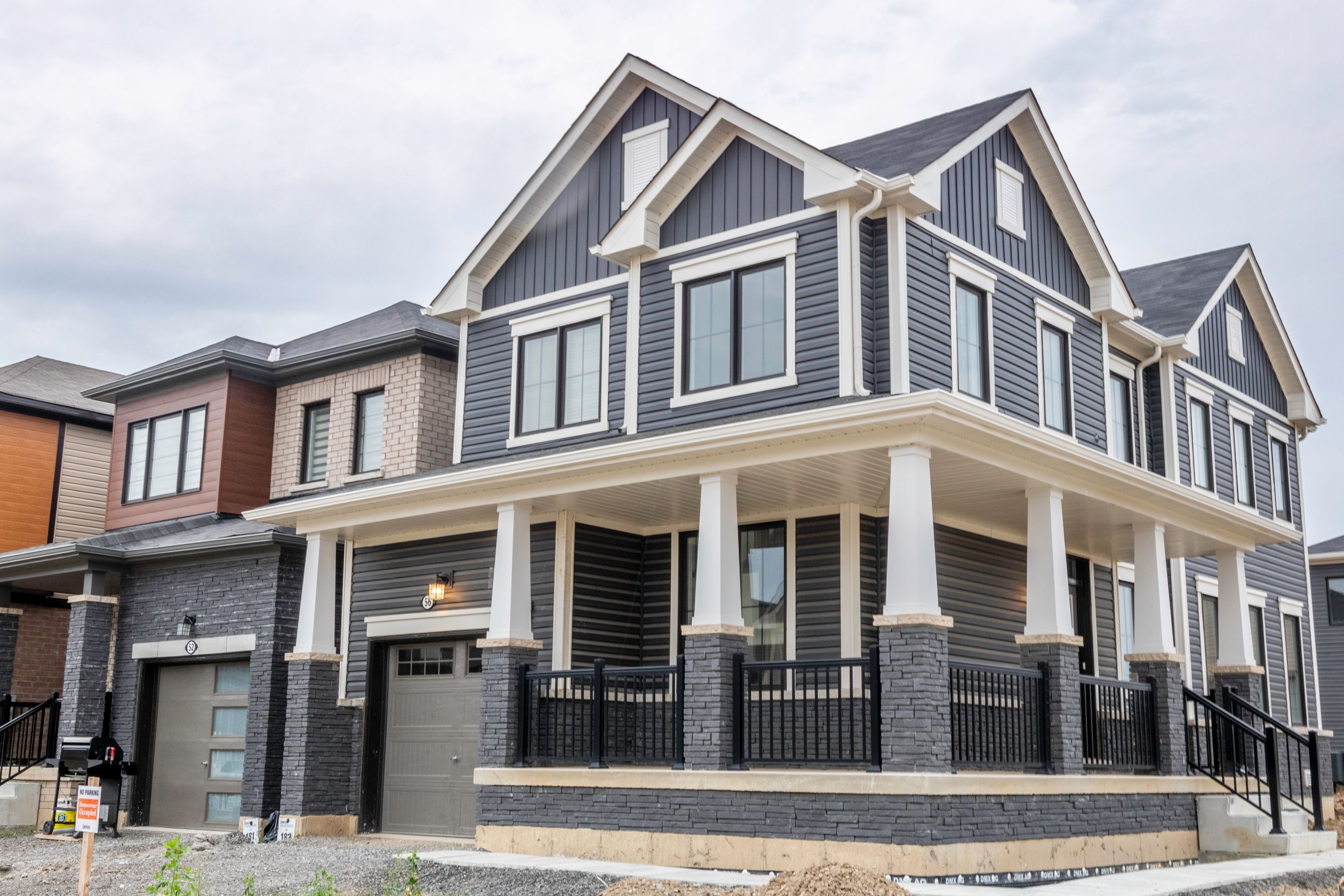 Row of modern townhouses with grey and brown exterior finishes and architectural details.