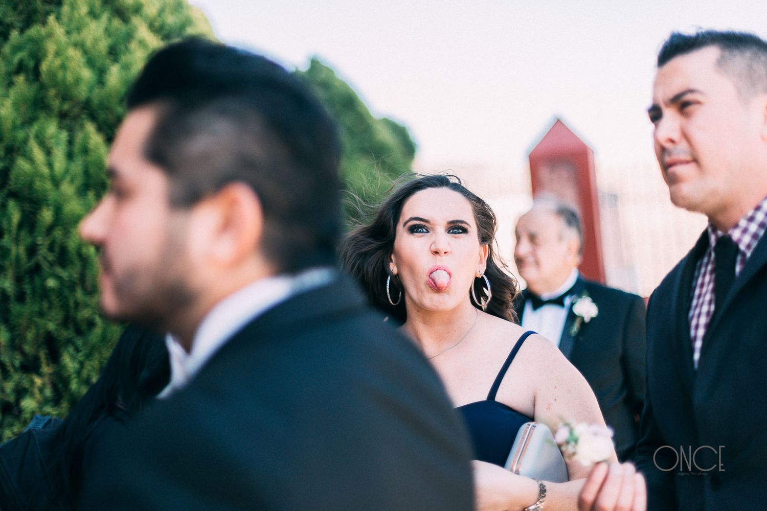 Wedding party group making playful expressions at outdoor venue.