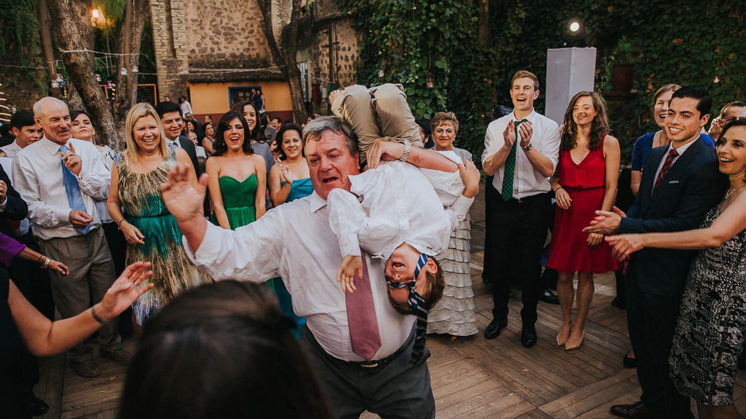 Wedding guests dance and celebrate on an outdoor patio venue.