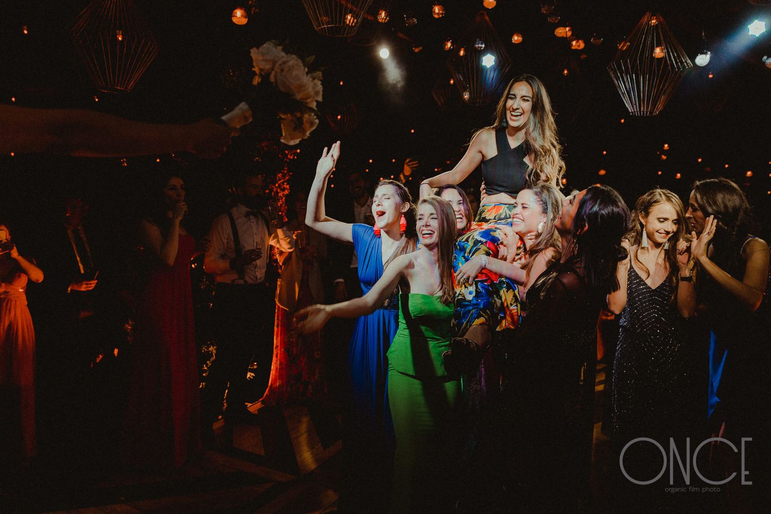 Energetic dance party with guests celebrating under warm lighting and decorative lanterns.