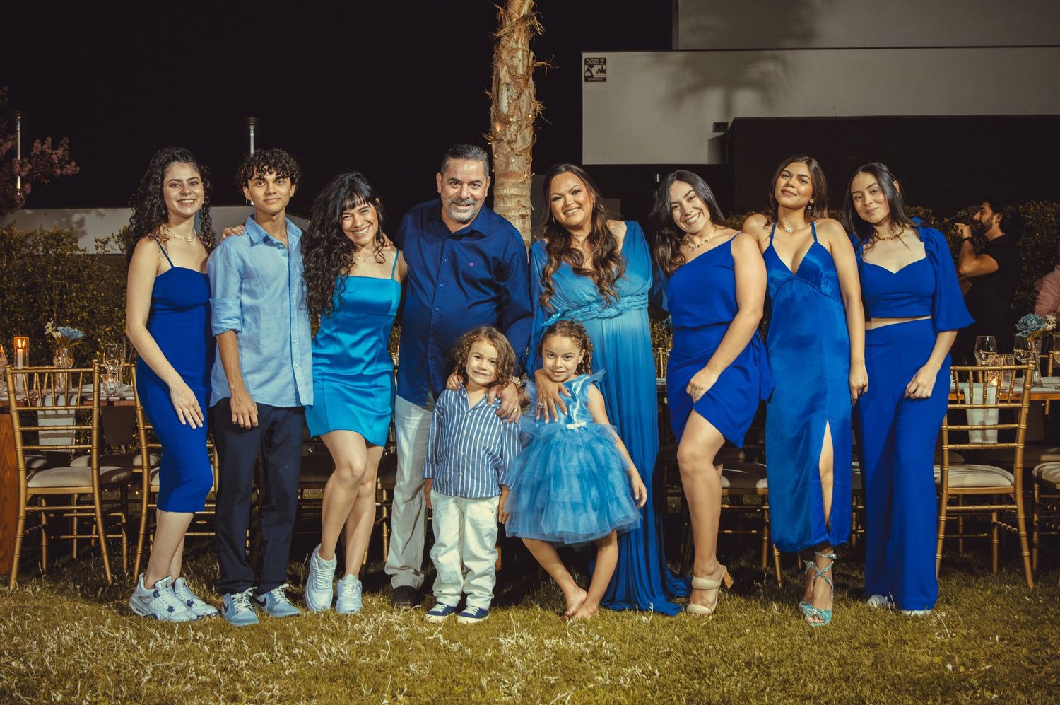 Group photo of people in matching blue attire arranged in rows outdoors.