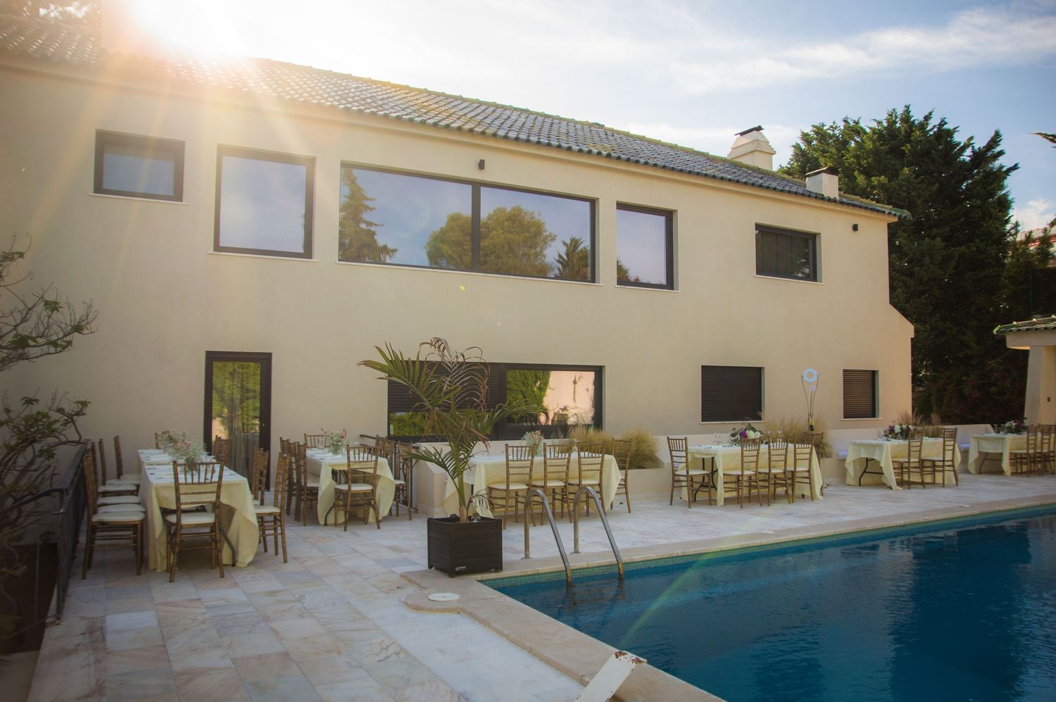 Modern villa with cream exterior features a pristine swimming pool and outdoor seating area.