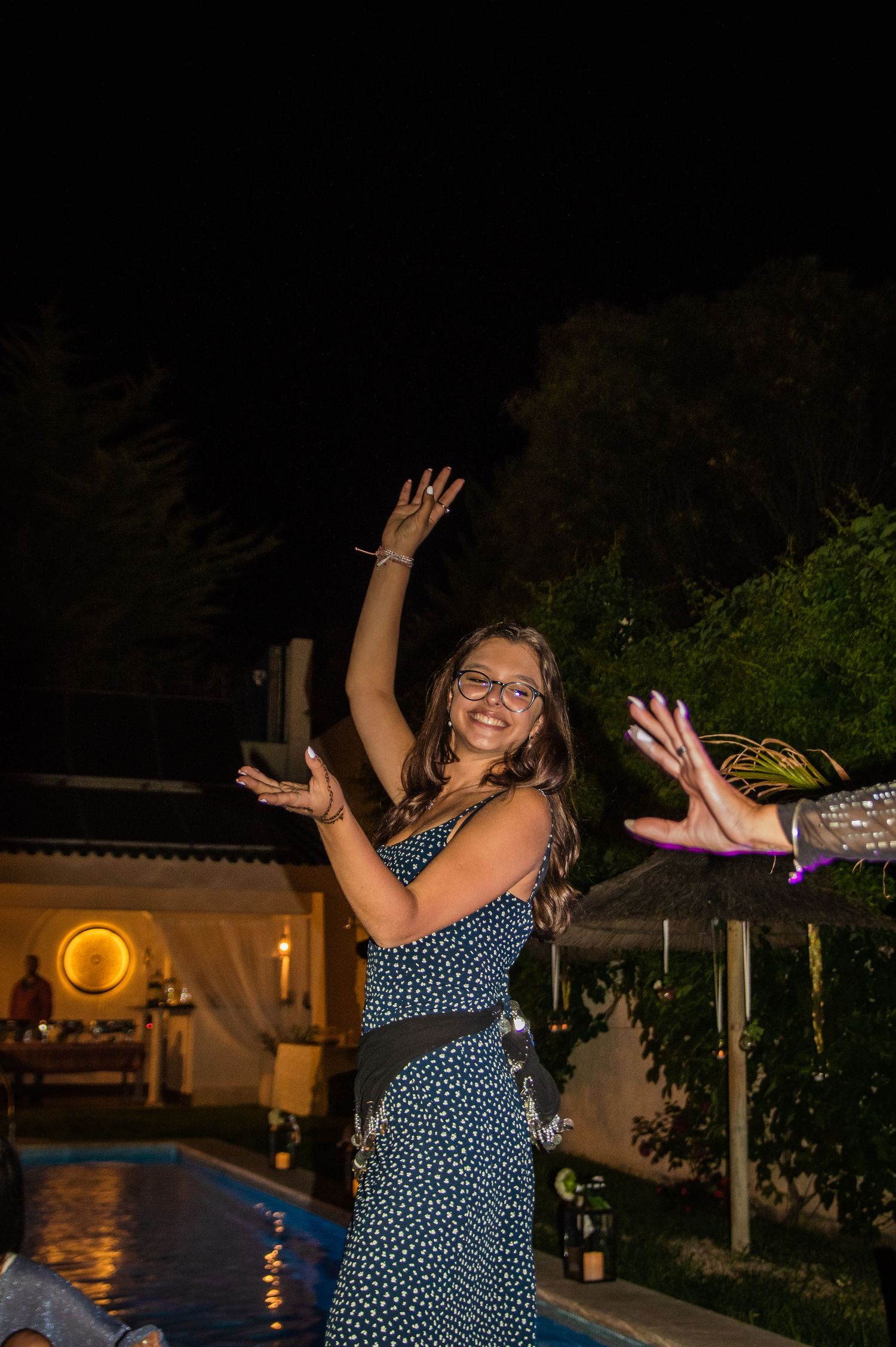 A polka dot dress-wearing dancer moves energetically at an outdoor nighttime party.
