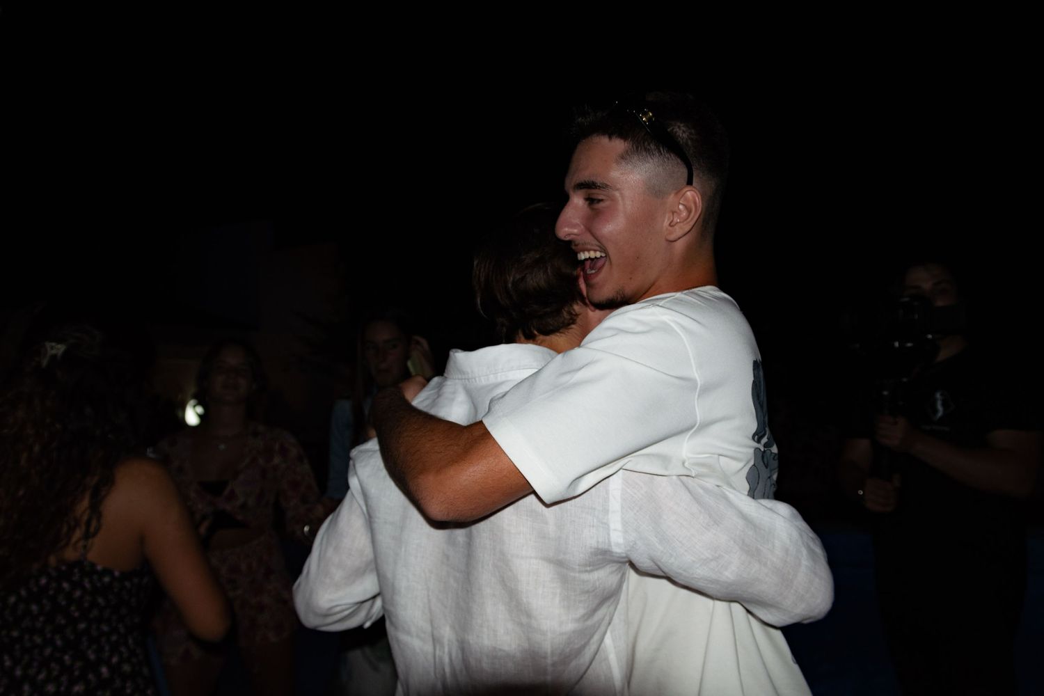 Couples slow dancing together at outdoor evening celebration.