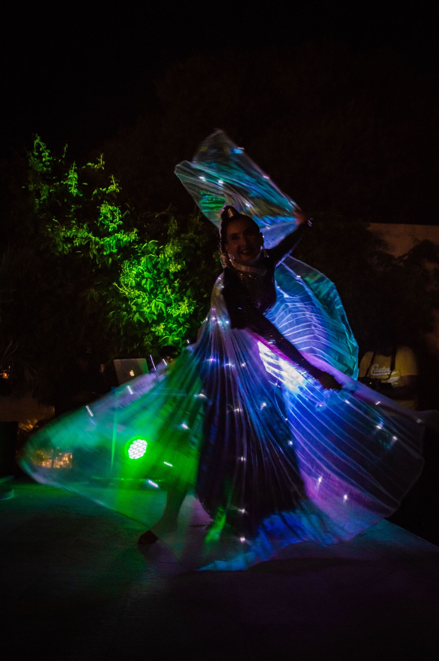 Long exposure night photography shows swirling blue and green LED lights creating artistic patterns in darkness.