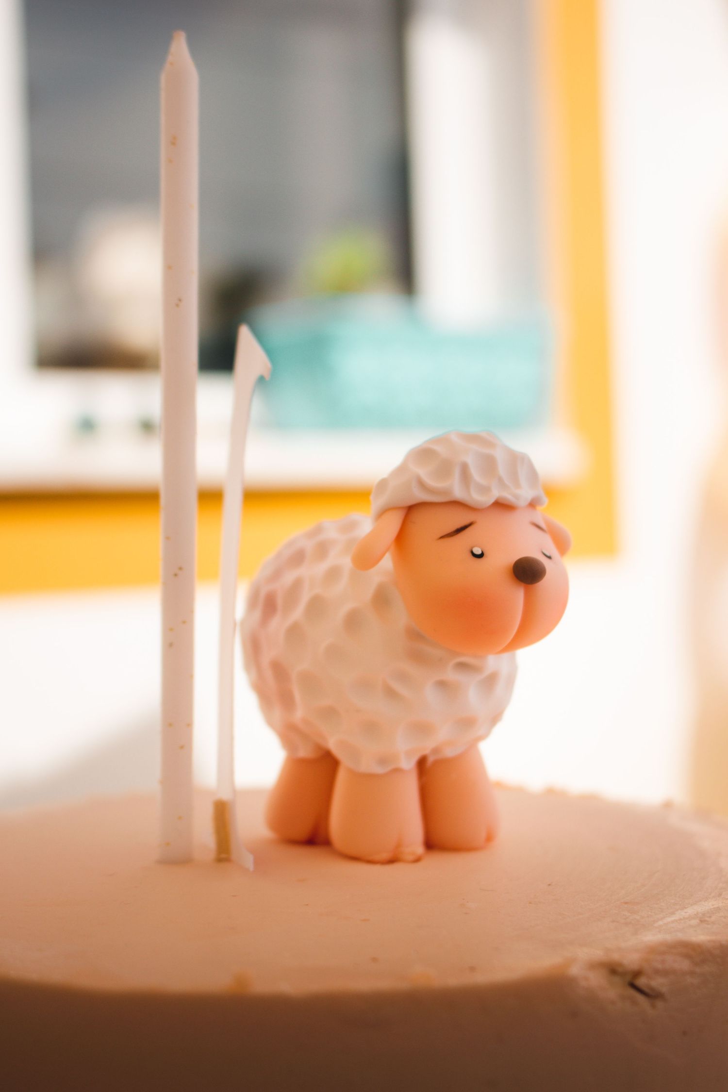Cute fondant sheep decoration with candle on top of cake.