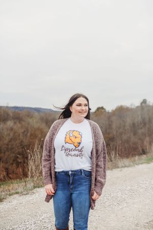 Person wearing pumpkin graphic t-shirt and cardigan in outdoor fall setting.