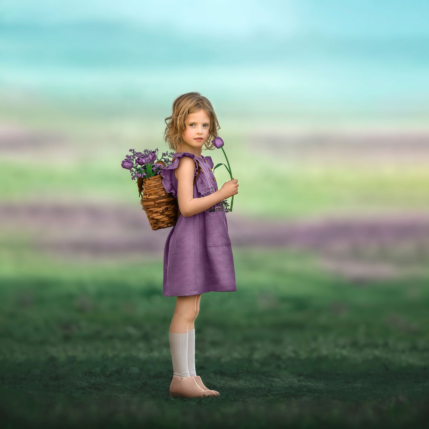Dreamy portrait of a child in a purple dress wearing a basket filled of tulips on her back, in a whimsical floral field.
