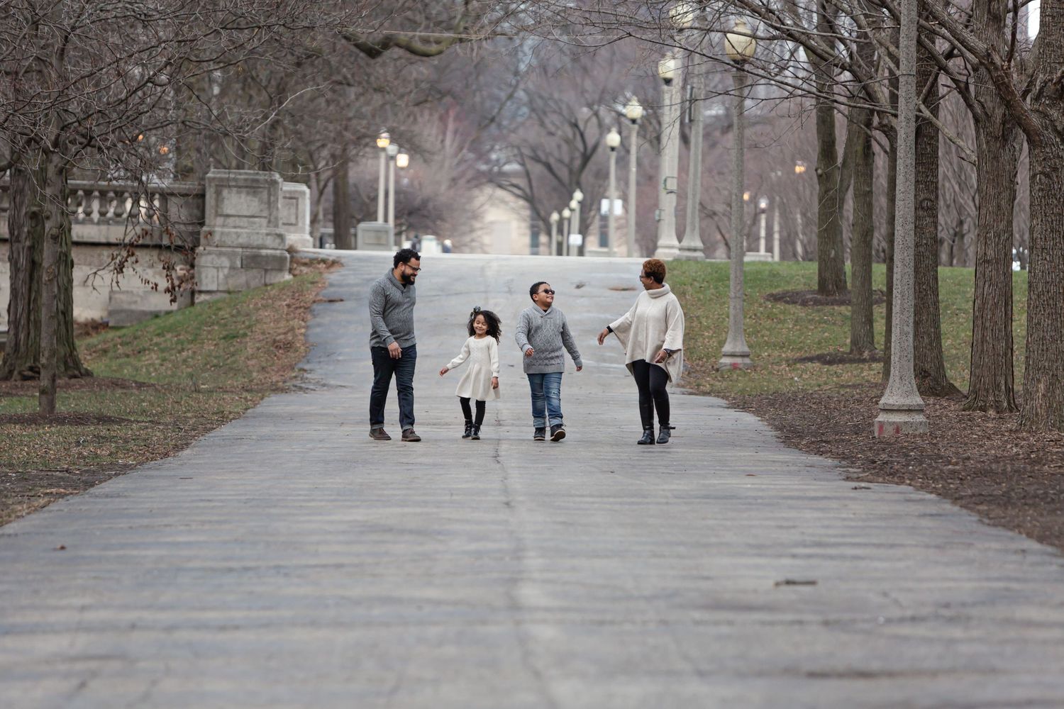 A silhouetted family walks down a tree-lined path on a misty day.