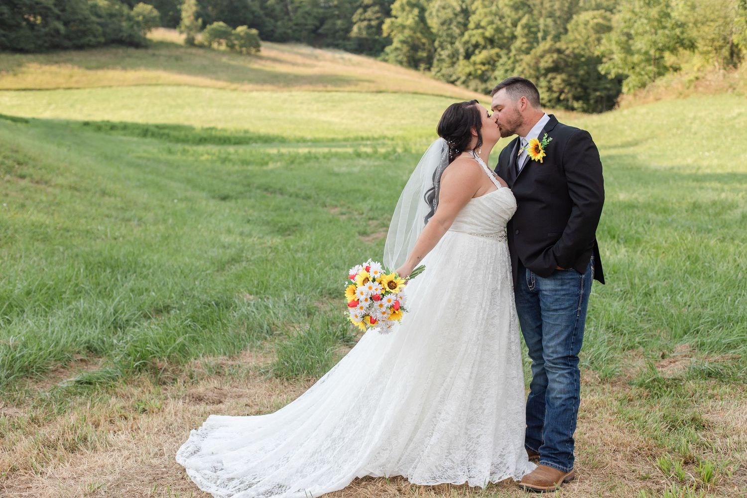 Romantic wedding portrait in a scenic field with flowing white dress and sunflower bouquet.