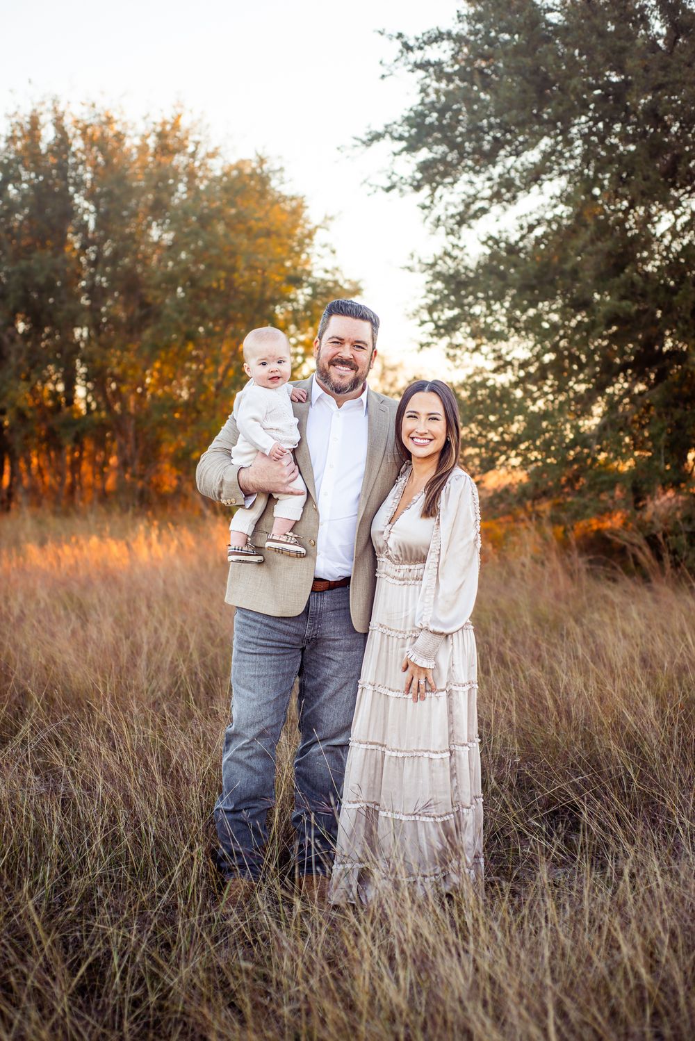 Family portrait in autumn field during golden hour.