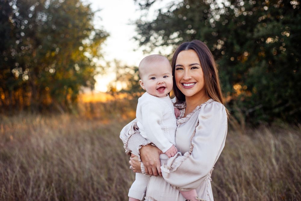 Mother and baby portrait in autumn field at sunset.