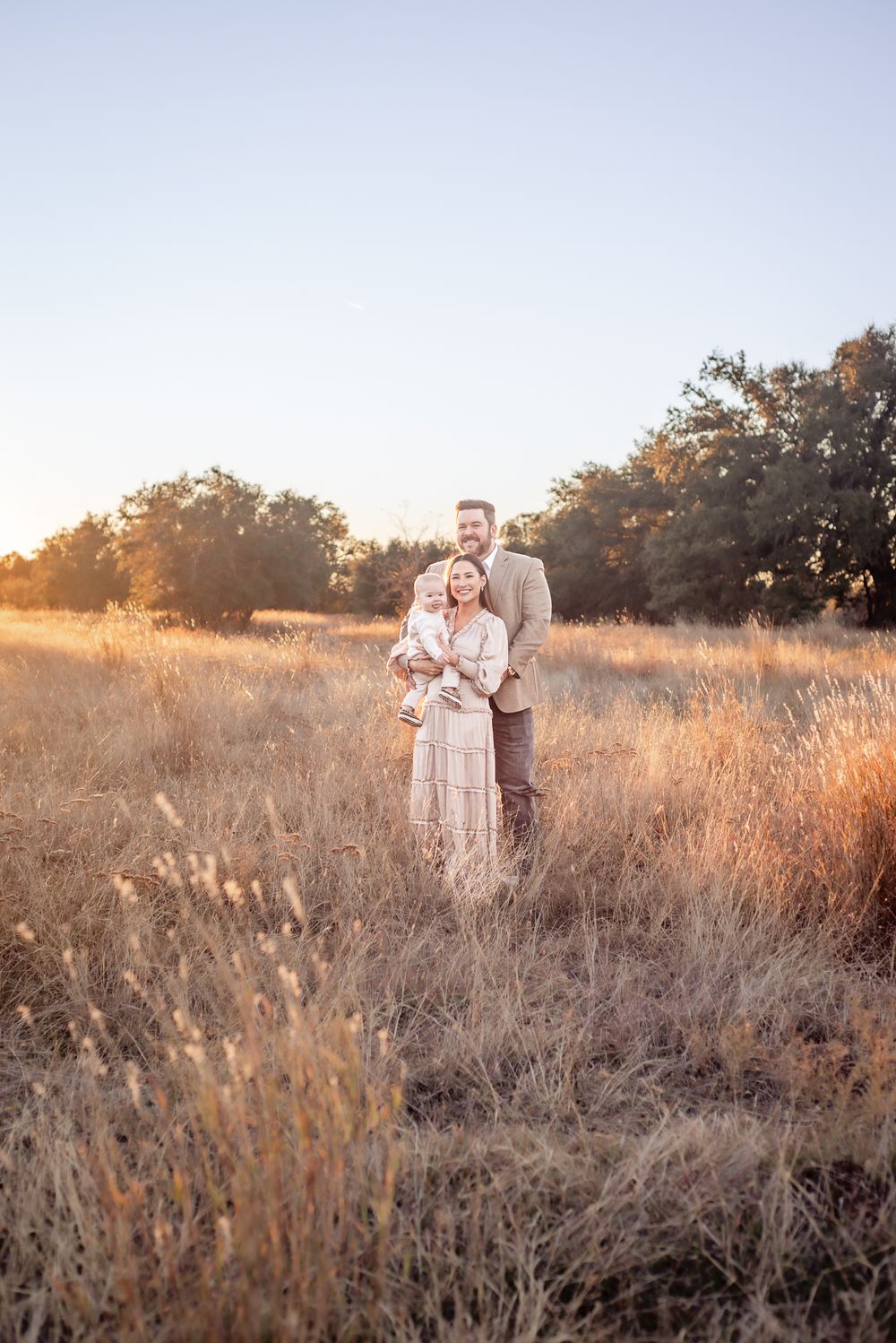 Golden sunset family photo in a rustic field with tall grass.
