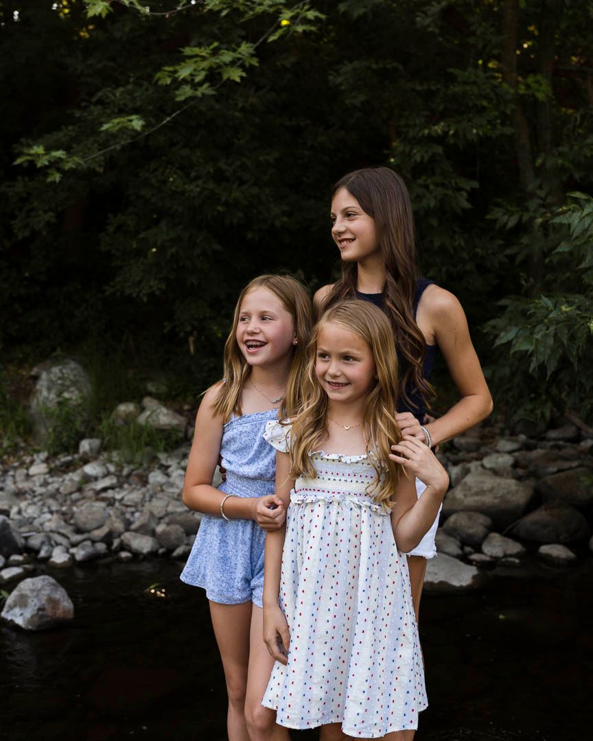A family of sisters playing in the water during a family photoshoot at the Sauk River Park in Sartell, Minnesota