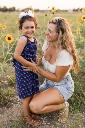 Young daughter and mother laughing in a sunflower field