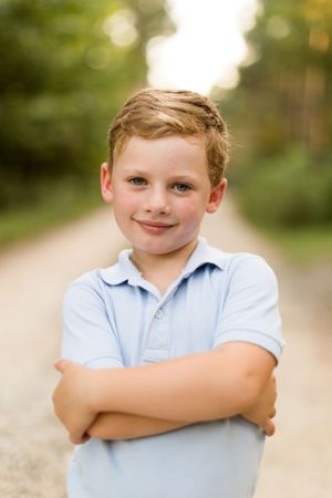 Smiling boy with arms crossed in a park