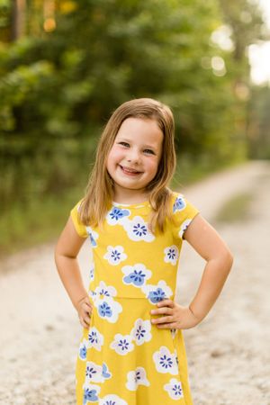 Smiling young girl with hands on hip on wooded path