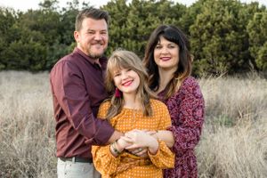 Smiling parents with daughter in field in Austin, Texas park