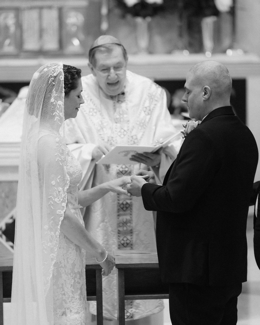 Traditional church wedding ceremony with priest officiating exchange of rings.