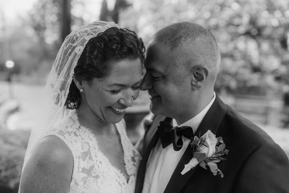 A tender moment between newlyweds sharing laughter during an outdoor wedding photoshoot.