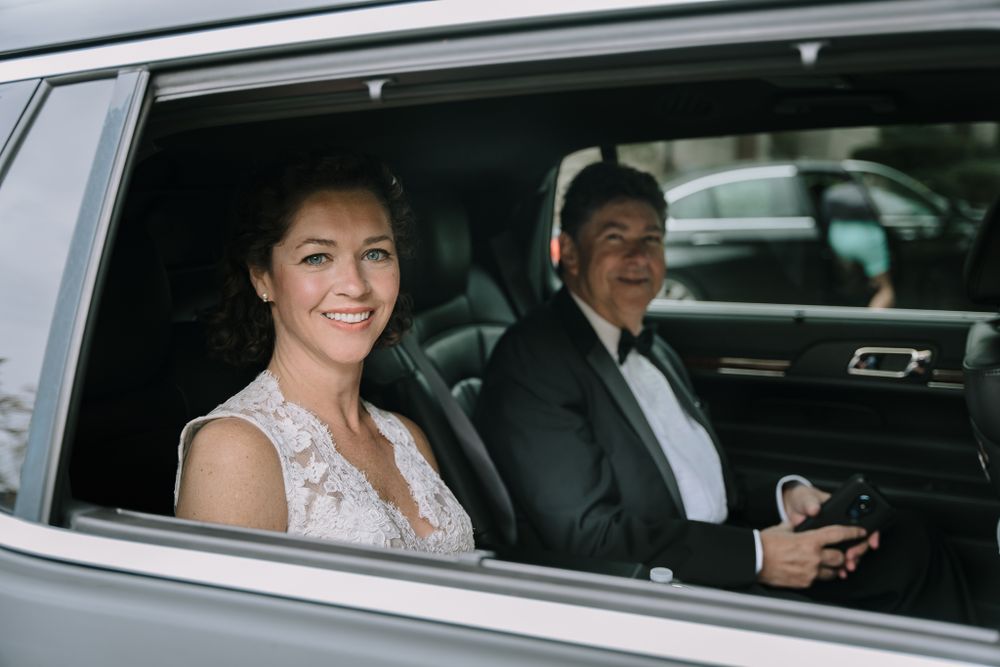 Wedding party passengers seated in a luxury car with tinted windows.