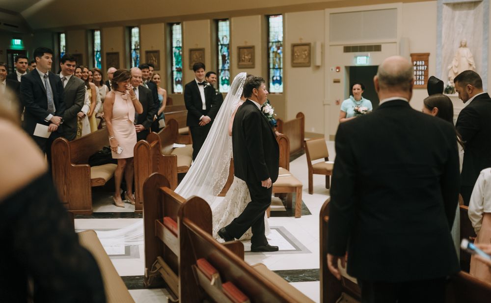 A wedding ceremony taking place in a traditional church with wooden pews and gathered guests.