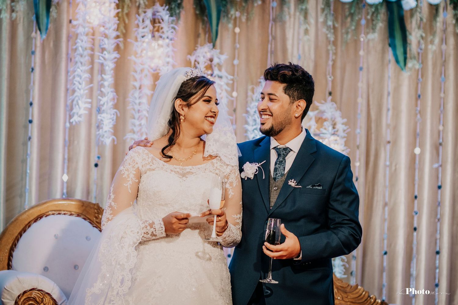 Newlyweds share a joyful moment while reading from a phone during their wedding reception.