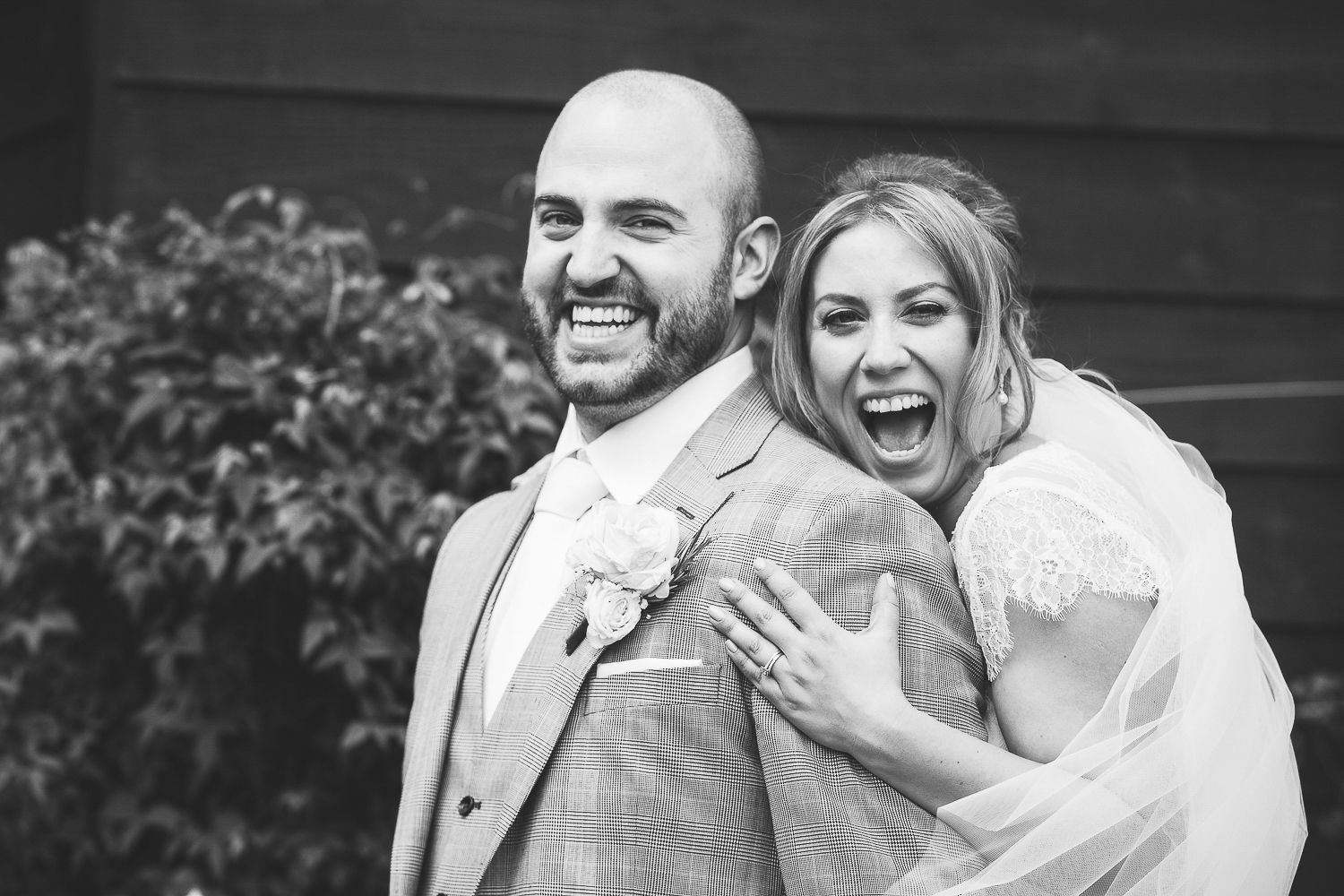 Black and white portrait of newlyweds sharing a candid laughing moment.