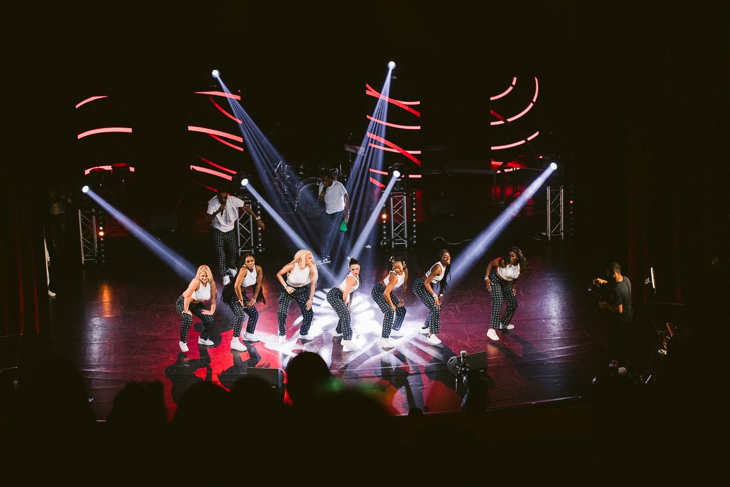 Dark stage performance with dramatic lighting and silhouetted dancers.