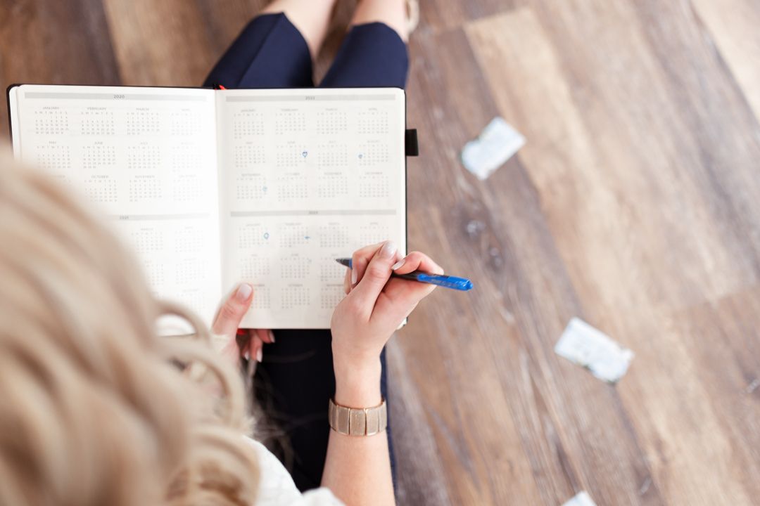Self-employed woman holding a planner and marking important dates with hearts. Business content for social media
