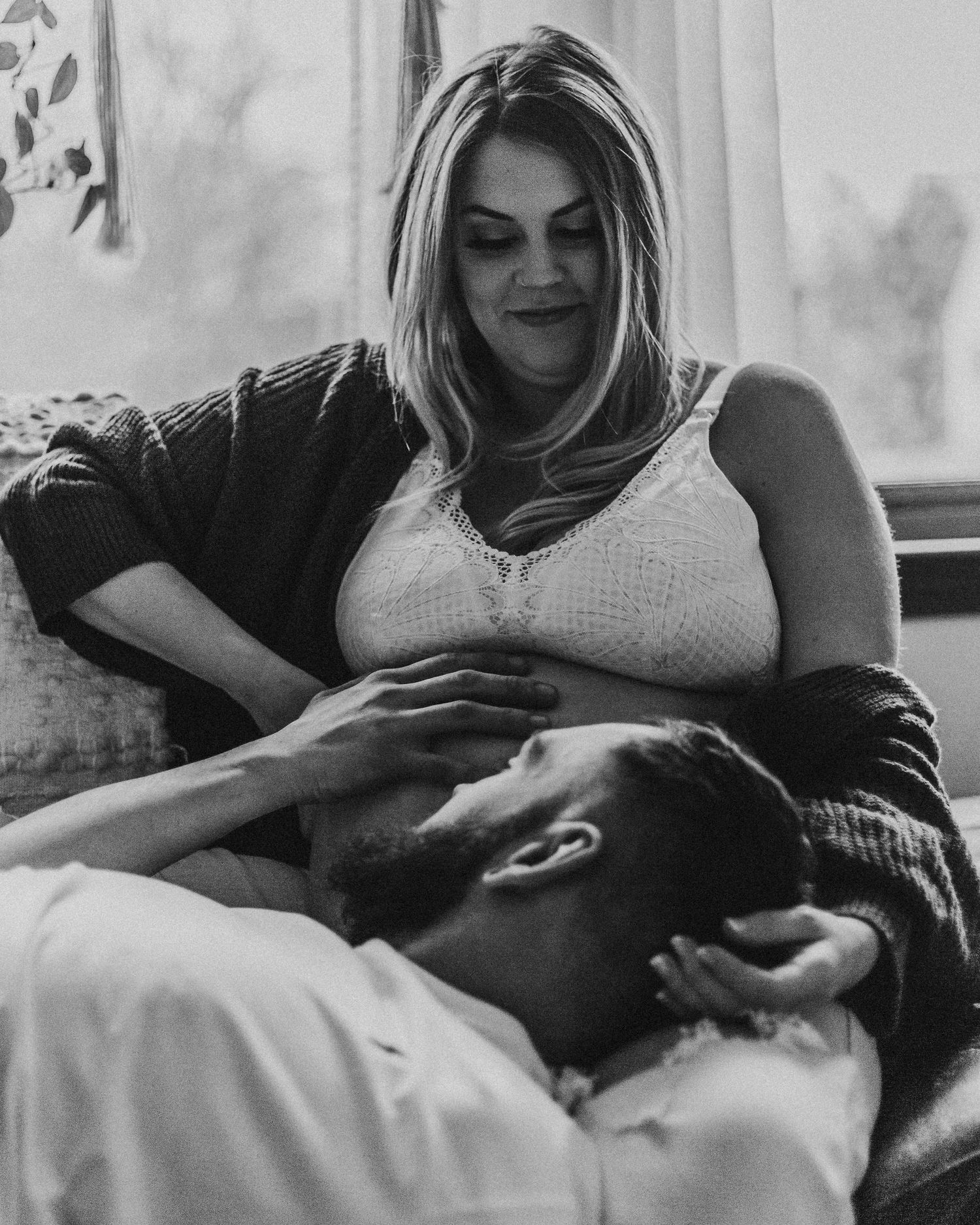 Intimate black and white photo of a couple sharing a tender moment together on a couch.