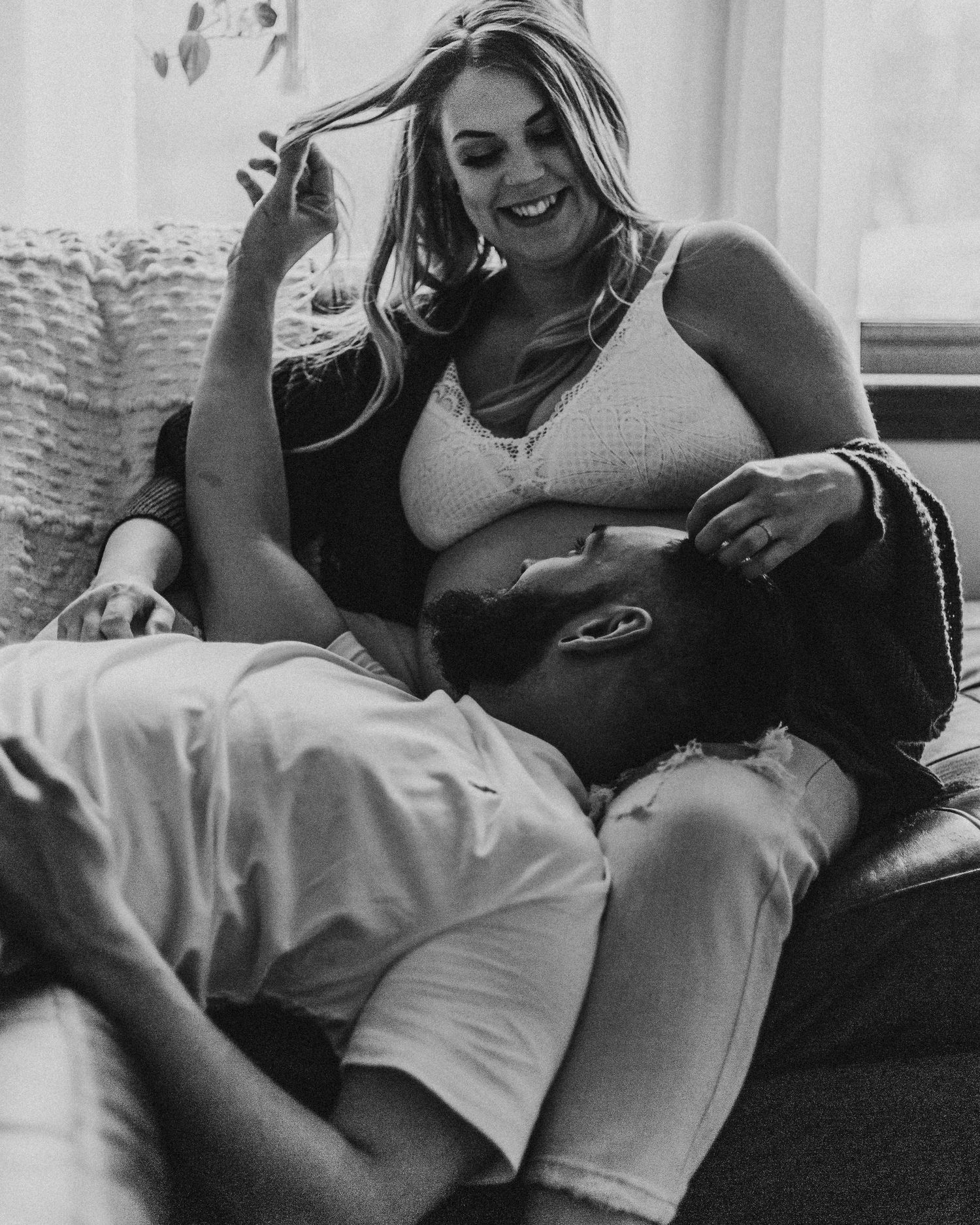 Happy couple laughing together while relaxing on a comfortable couch in natural lighting.