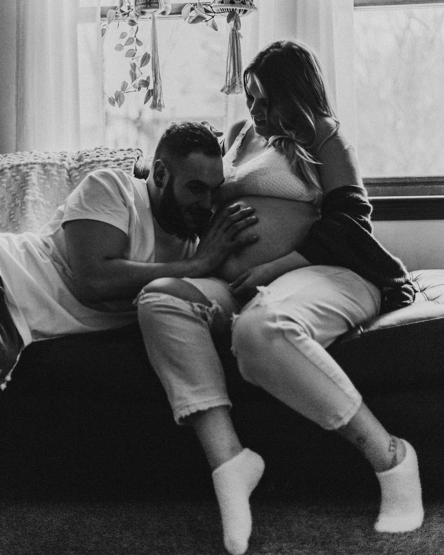 Tender maternity moment shared between expecting couple on a couch.