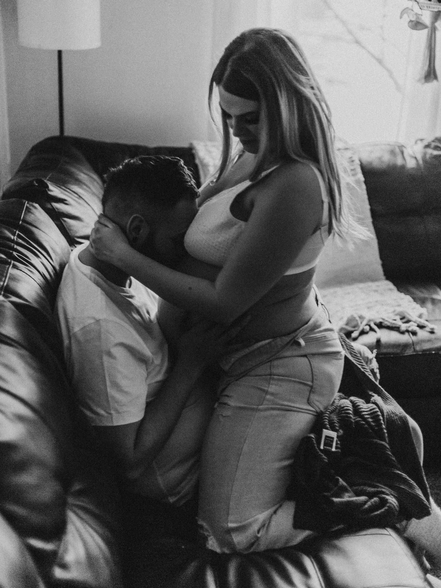 Black and white intimate portrait of couple sharing tender moment on couch.