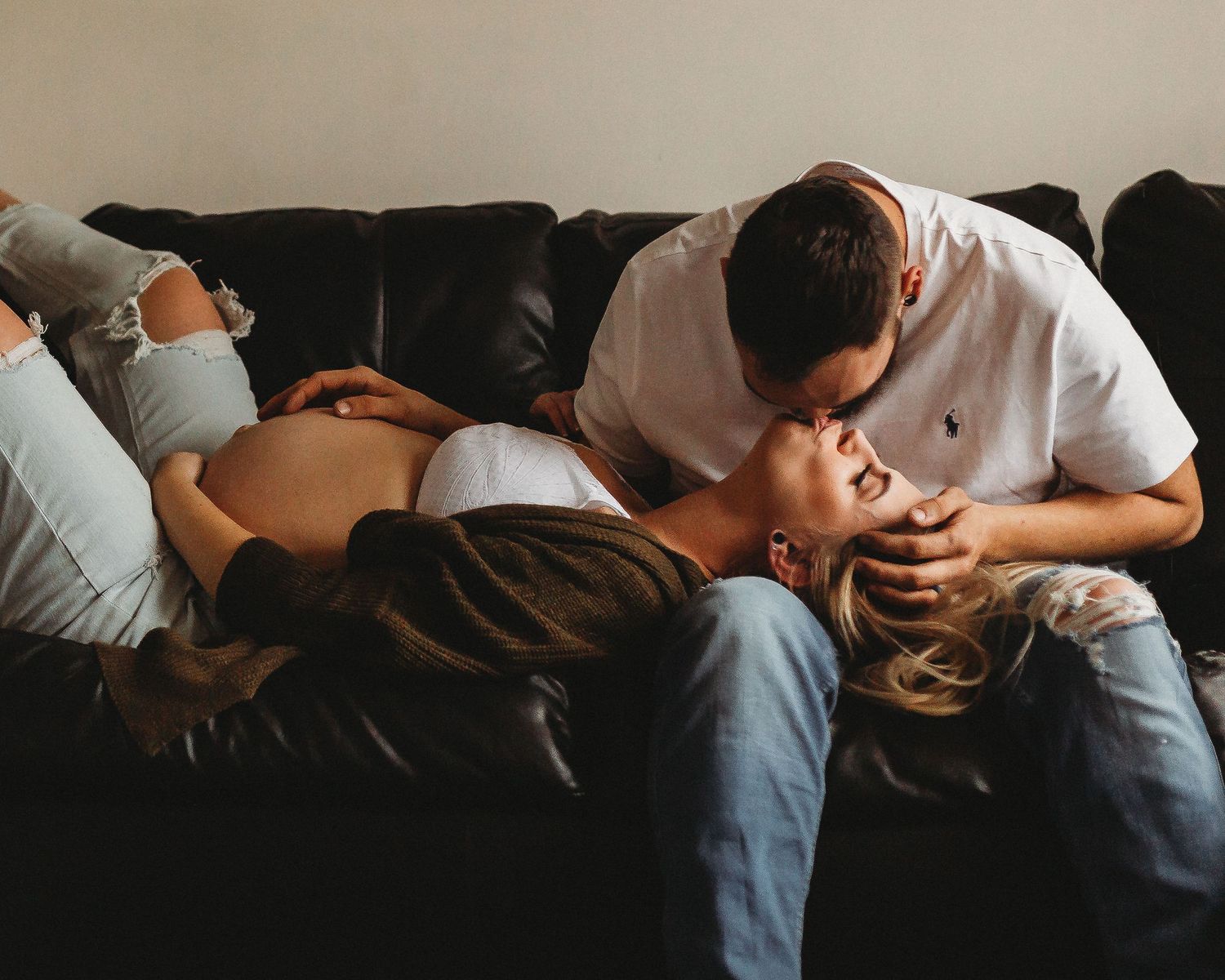 Intimate lifestyle portrait of couple sharing tender moment on leather sofa.