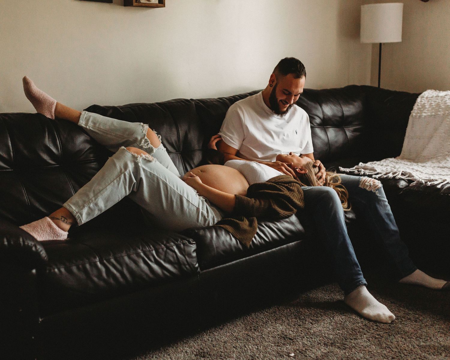 Casual lifestyle photo of couple relaxing together on black leather sofa.